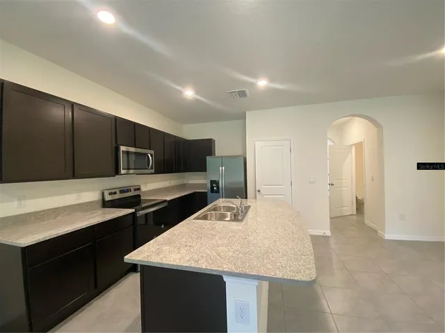 a kitchen with stainless steel appliances kitchen island granite countertop a sink and cabinets
