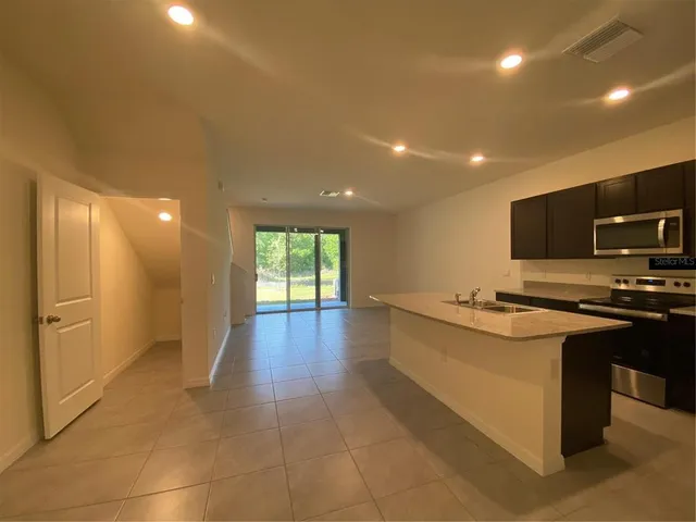 a large kitchen with stainless steel appliances a large counter top a stove and a refrigerator