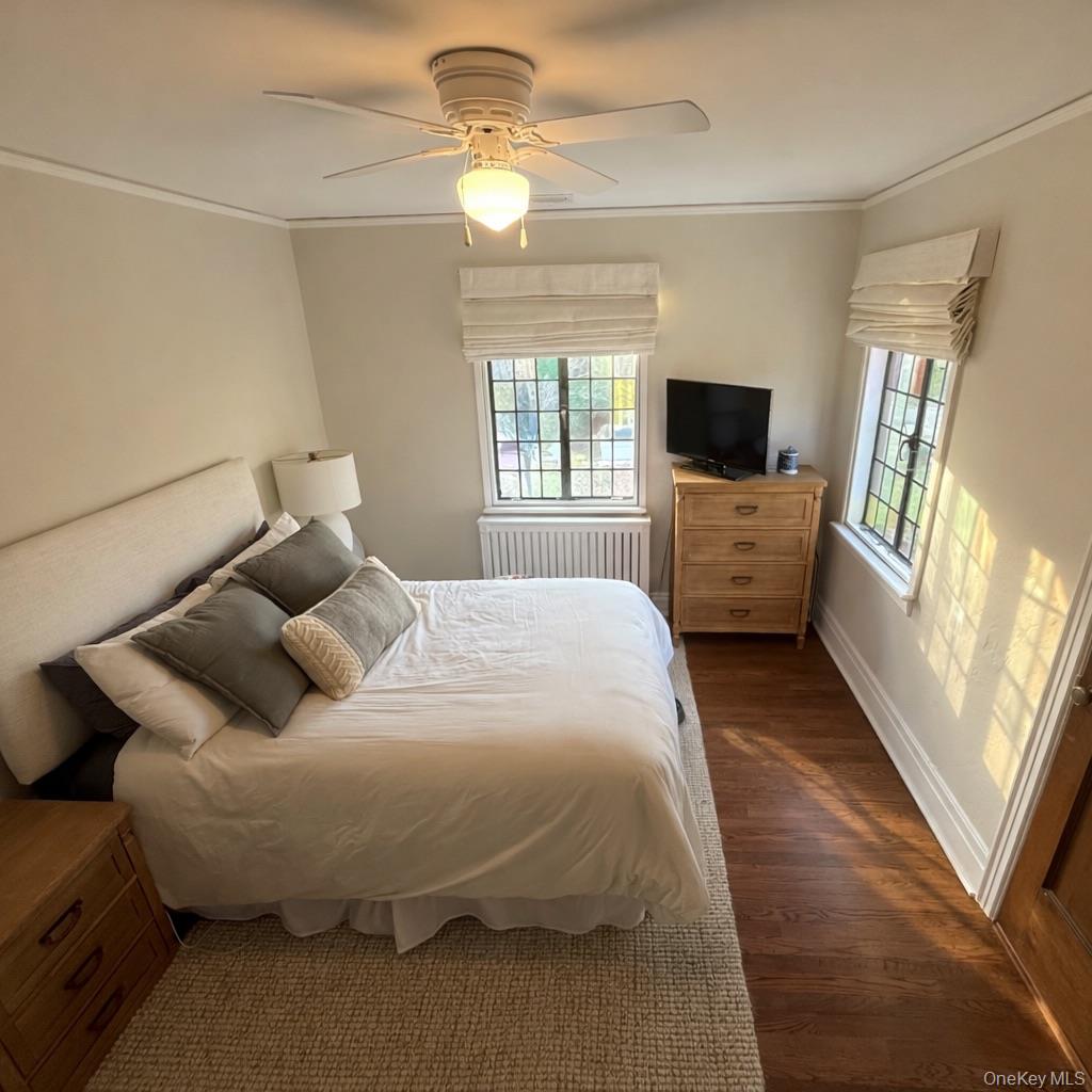 461 North Long Beach Road Rockville Centre, NY 11570 - Photo 11 of 14 Bedroom with multiple windows, radiator, dark wood finished floors, a ceiling fan, and ornamental molding