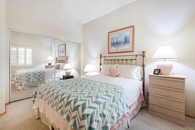 a bedroom with a bed and a lamp on dresser