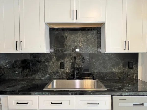 a kitchen with granite countertop white cabinets and a stove
