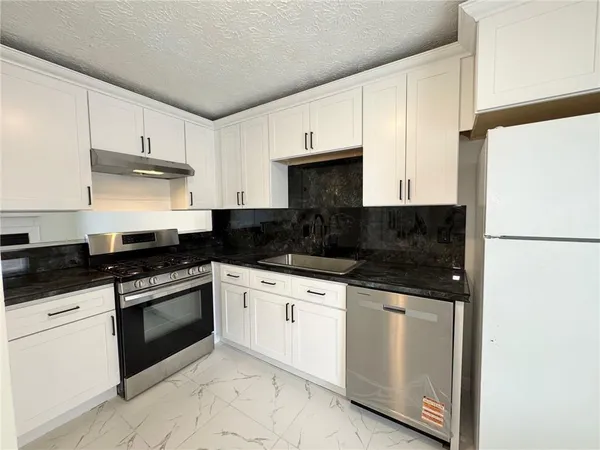 a kitchen with white cabinets and black appliances
