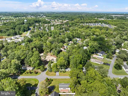 an aerial view of a residential houses with outdoor space and trees all around