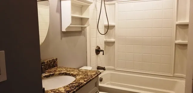 a bathroom with a granite countertop sink a mirror and a shower