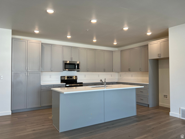 717 West W Coho Lane South, Unit 2F302 Midvale, UT 84047 - Photo 7 of 22 Modern kitchen featuring gray cabinetry, stainless steel appliances, a center island with sink, white countertops, and wood-finish flooring