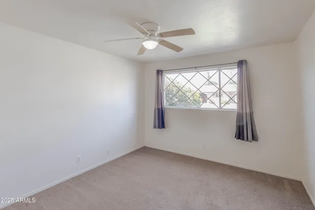 an empty room with a ceiling fan and window