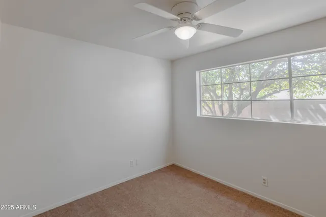 an empty room with a window and a fan