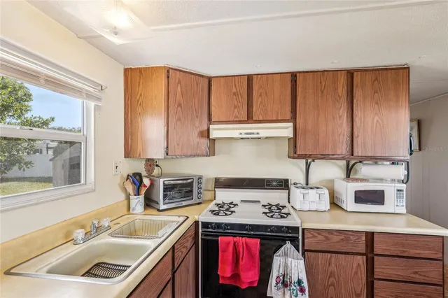 a kitchen with kitchen island granite countertop a sink stove and cabinets
