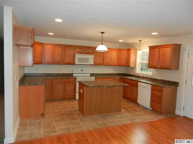 7595 Woodleaf Road Woodleaf, NC 27054 - Photo 3 of 16 a kitchen with kitchen island granite countertop wooden cabinets and a stove