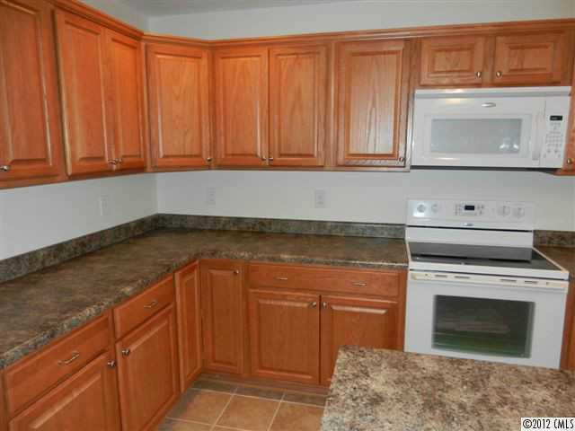 7595 Woodleaf Road Woodleaf, NC 27054 - Photo 4 of 16 a kitchen with granite countertop stainless steel appliances white cabinets and a wooden floor