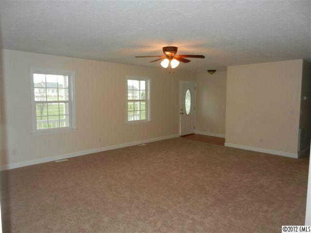 7595 Woodleaf Road Woodleaf, NC 27054 - Photo 5 of 16 an empty room with windows and chandelier fan