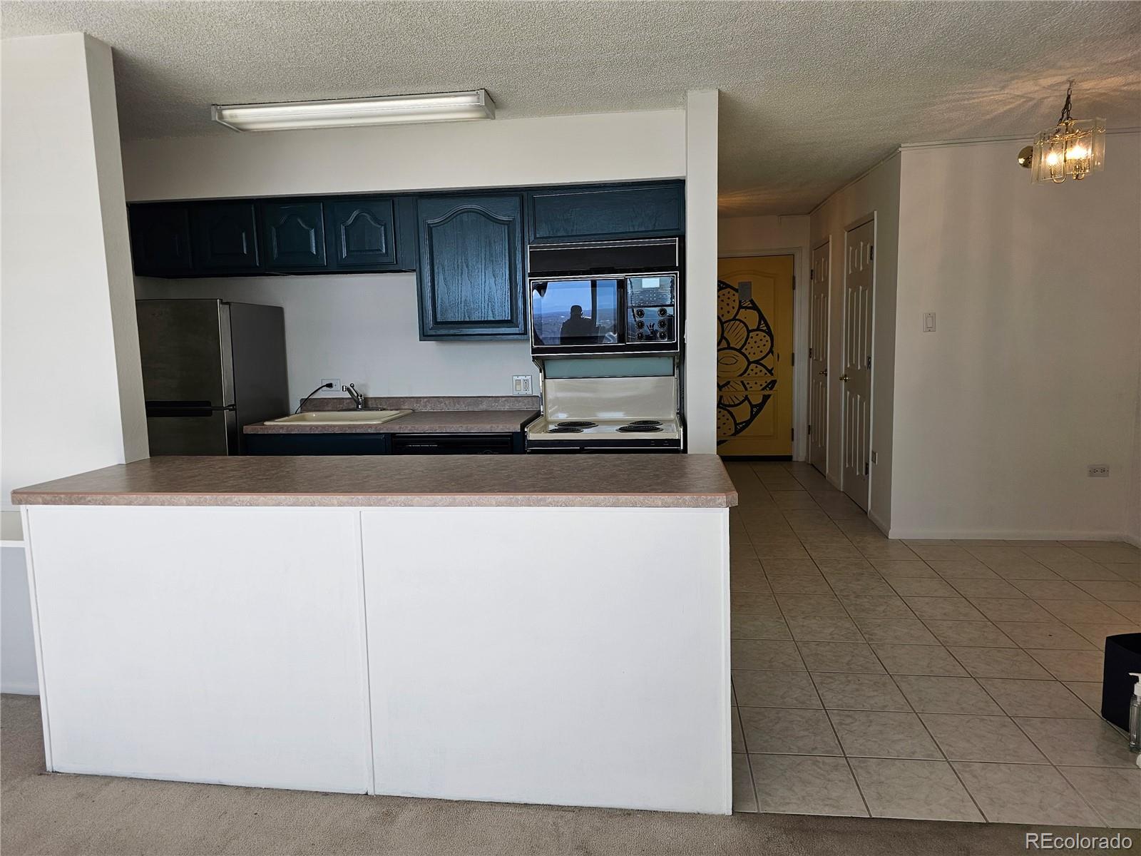 1020 15th Street, Unit 33B Denver, CO 80202 - Photo 12 of 48 a kitchen with kitchen island granite countertop a refrigerator a sink and a stove