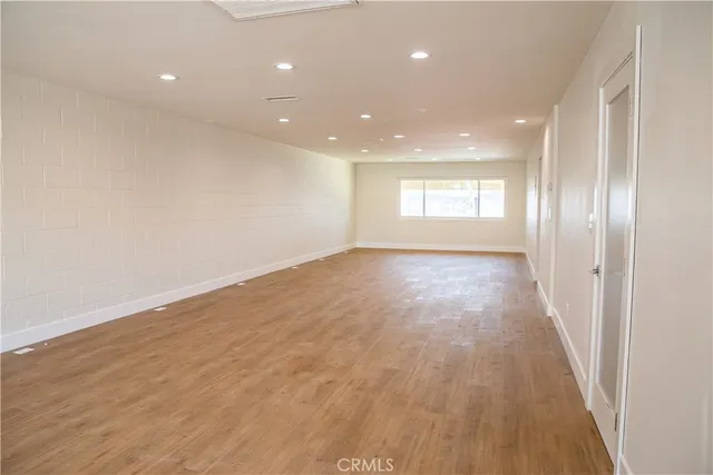 a view of an empty room with wooden floor and window