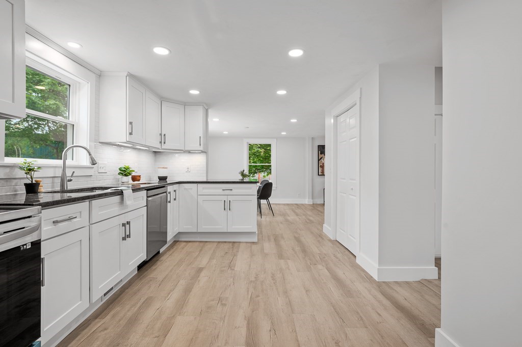 91 Schofield Avenue Dudley, MA 01571 - Photo 11 of 27 a white kitchen with wooden floor and stainless steel appliances