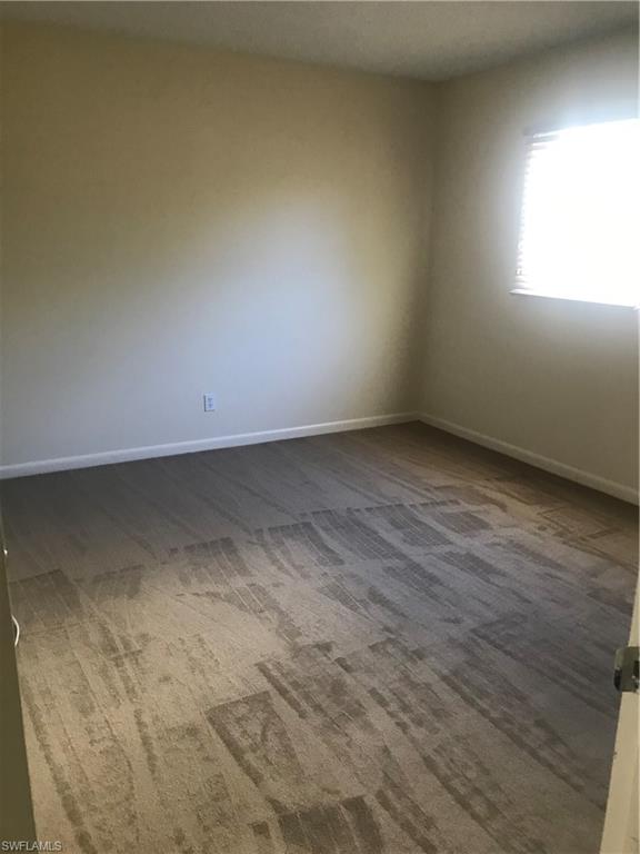 216 Banyan Boulevard, Unit 216 Naples, FL 34102 - Photo 17 of 33 an empty room with wooden floor and windows