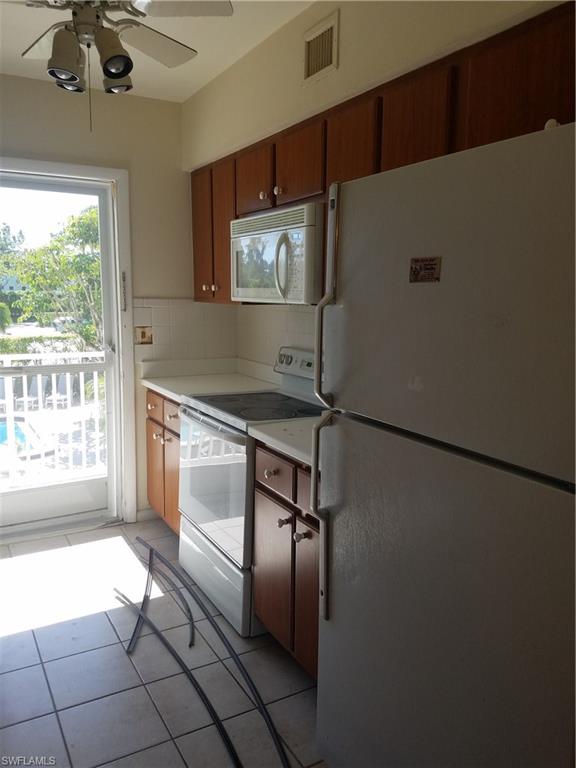 216 Banyan Boulevard, Unit 216 Naples, FL 34102 - Photo 7 of 33 a kitchen with kitchen island a counter top space appliances and a large window
