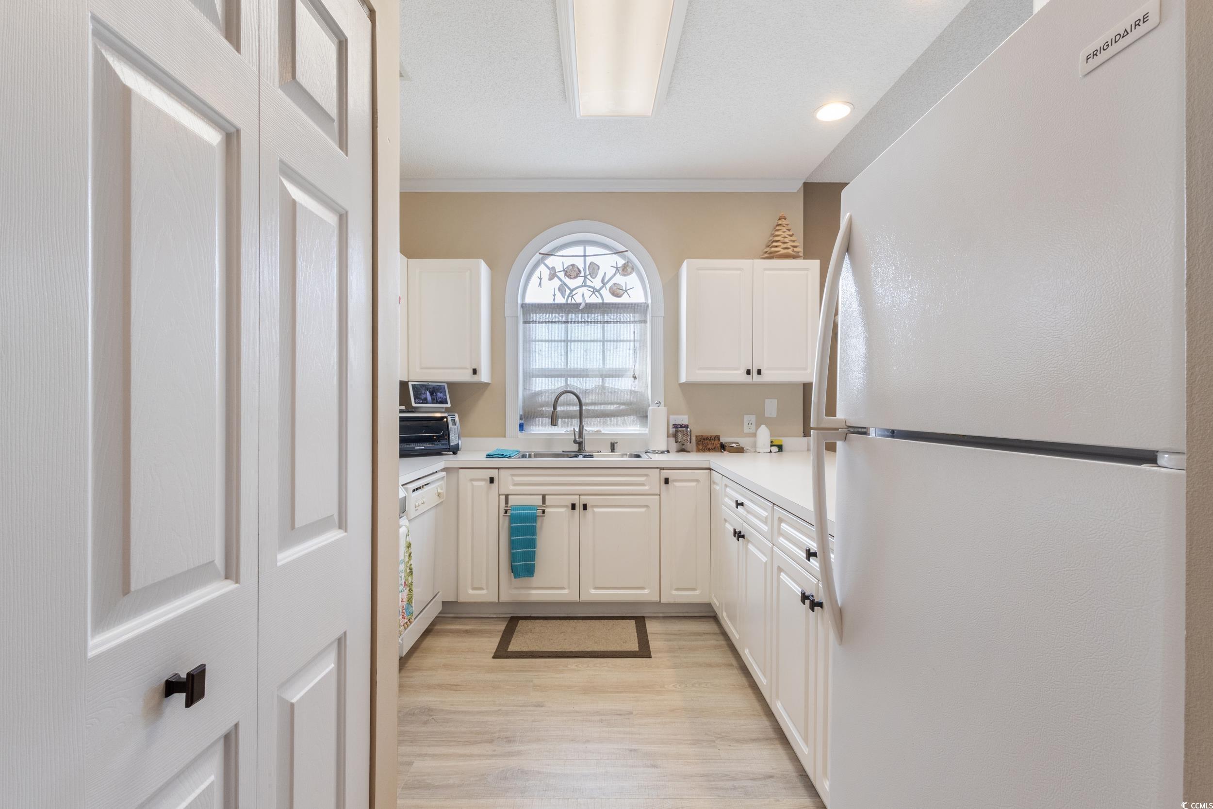 4781 Wild Iris Drive, Unit 301 Myrtle Beach, SC 29577 - Photo 13 of 33 Kitchen featuring white appliances, white cabinets, light countertops, and ornamental molding