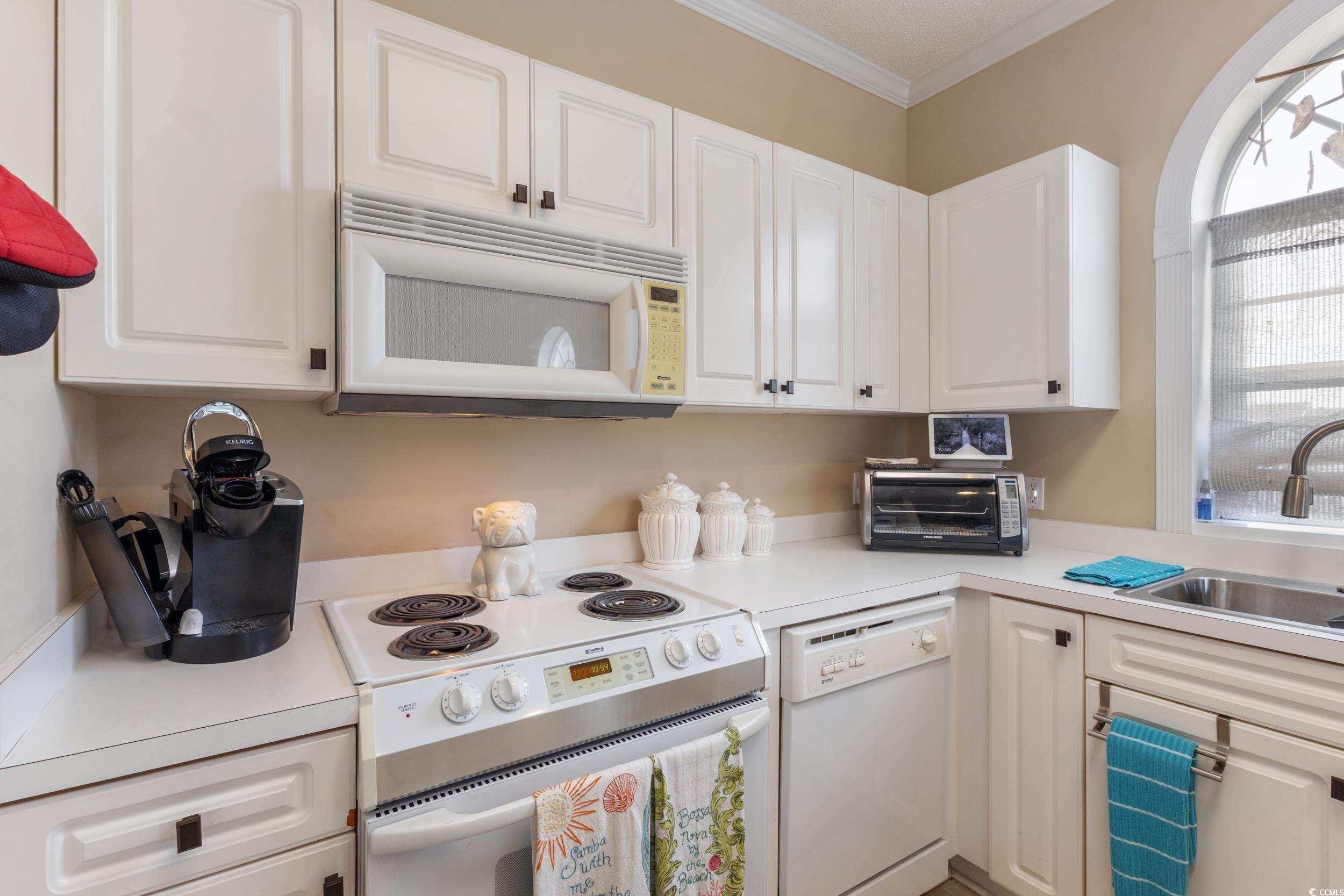4781 Wild Iris Drive, Unit 301 Myrtle Beach, SC 29577 - Photo 14 of 33 Kitchen featuring white appliances, white cabinets, light countertops, and ornamental molding