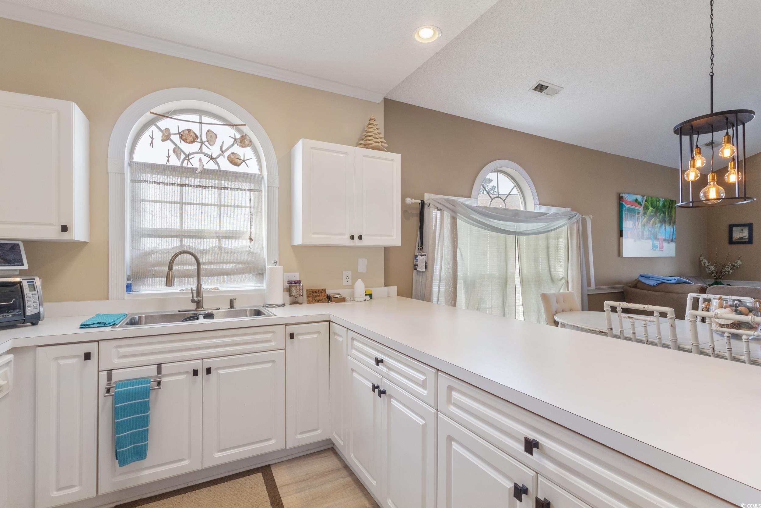 4781 Wild Iris Drive, Unit 301 Myrtle Beach, SC 29577 - Photo 25 of 33 Kitchen with white cabinets, light countertops, and pendant lighting