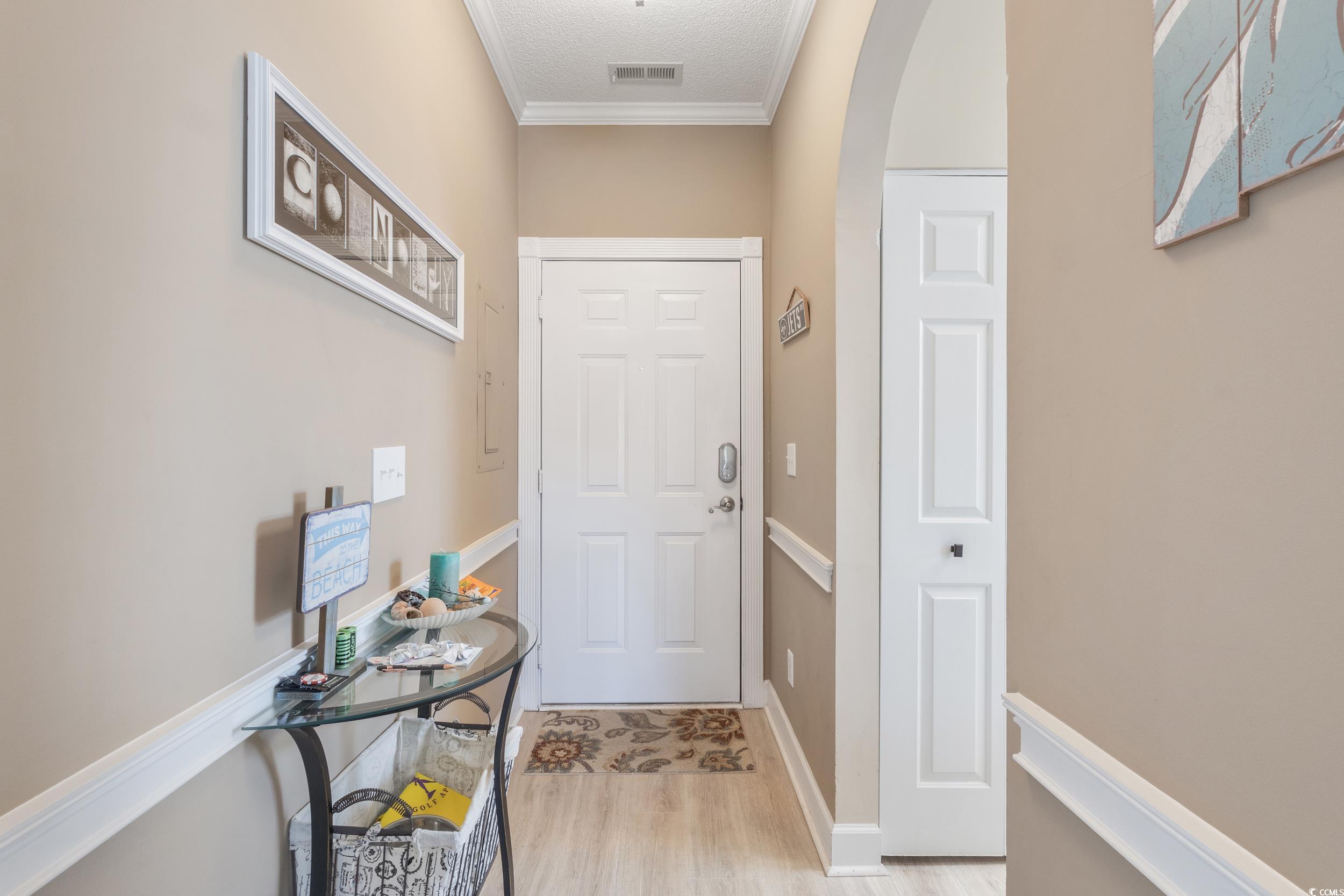4781 Wild Iris Drive, Unit 301 Myrtle Beach, SC 29577 - Photo 26 of 33 Entryway featuring arched walkways, crown molding, wood finished floors, and a textured ceiling