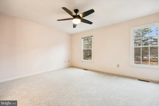 an empty room with window and ceiling fan