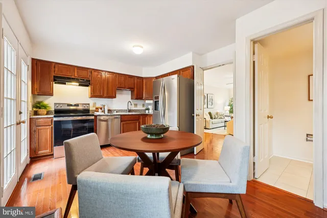 a kitchen with stainless steel appliances a dining table chairs and wooden floor