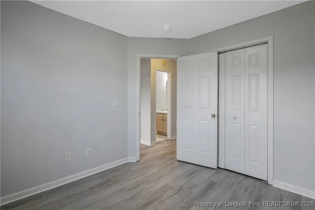 a view of an empty room with wooden floor and closet
