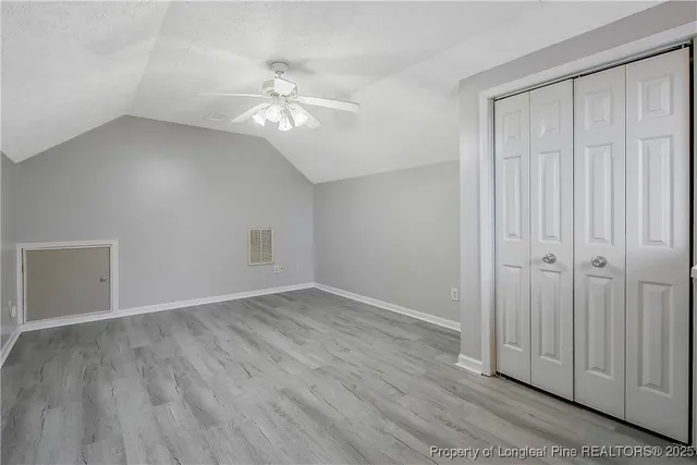 an empty room with wooden floor closet and fan