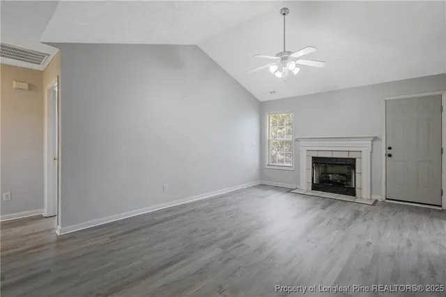 a view of an empty room with wooden floor fireplace and a window