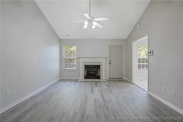 an empty room with wooden floor fireplace and windows