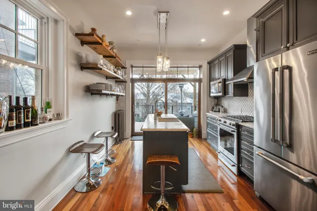 a view of a kitchen with kitchen island stainless steel appliances a stove a sink and a refrigerator