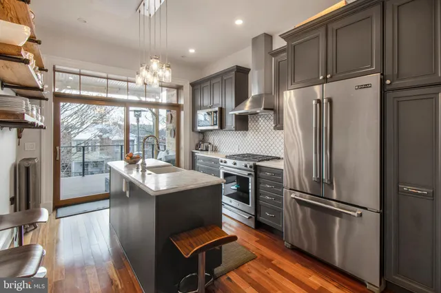 a kitchen with kitchen island a counter top space a sink stainless steel appliances and cabinets