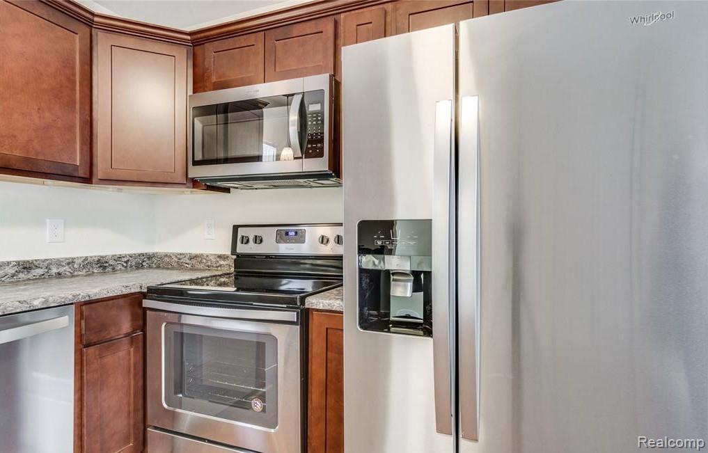 2365 Welch Road Walled Lake, MI 48390 - Photo 6 of 14 Kitchen featuring wood cabinetry, laminate countertops, and stainless steel appliances including a side-by-side refrigerator, microwave, and range