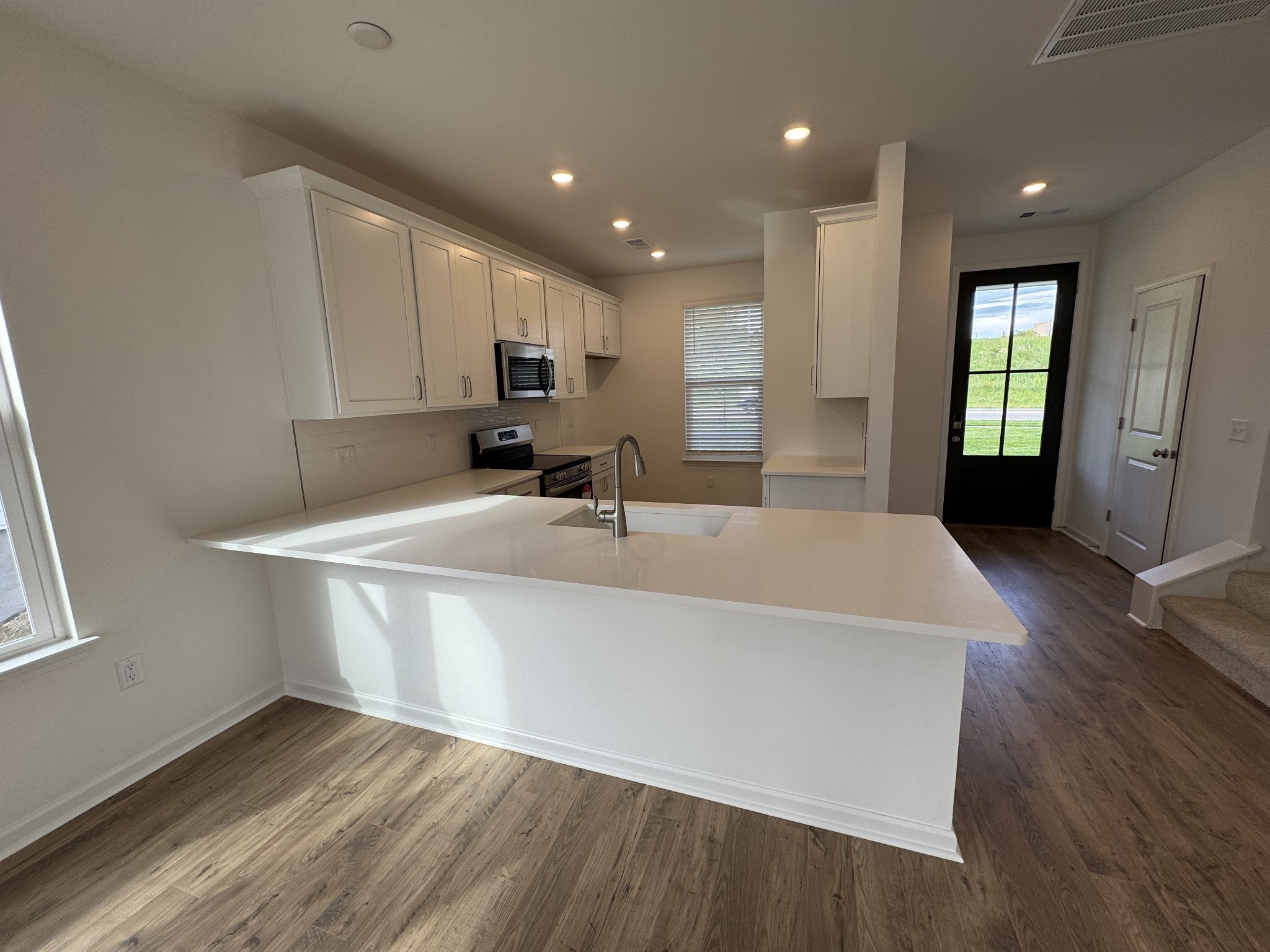 410 Blair Road Smyrna, TN 37167 - Photo 5 of 27 a large kitchen with stainless steel appliances a sink a microwave a refrigerator and white cabinets with wooden floor