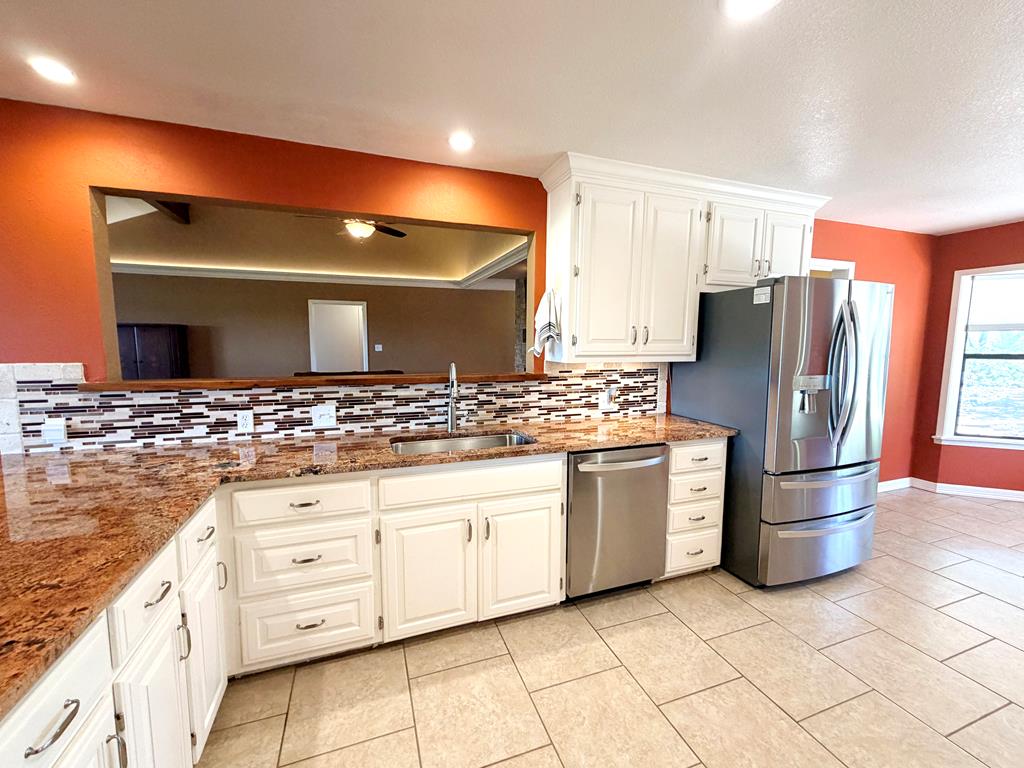 707 Rimrock Road Kerrville, TX 78028 - Photo 18 of 55 a kitchen with stainless steel appliances kitchen island granite countertop a refrigerator and a stove top oven