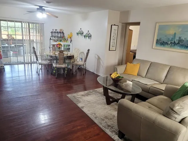 a living room with furniture a wooden floor and next to a window