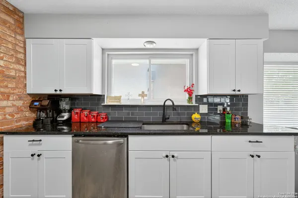 a kitchen with white cabinets and window