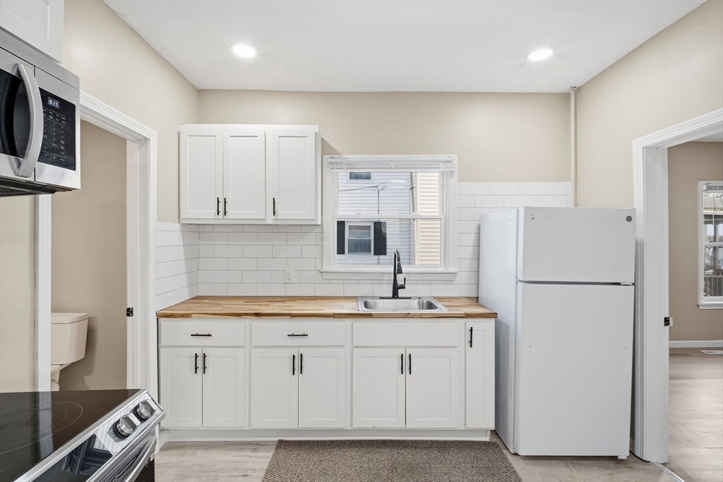 52 Osgood Street Springfield, MA 01107 - Photo 5 of 42 a kitchen with a sink a refrigerator a stove and white cabinets