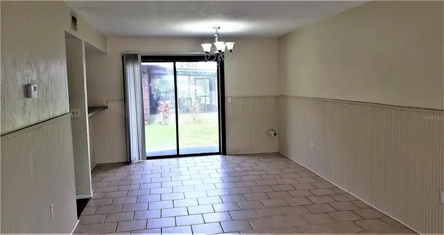 a view of a hallway with chandelier and glass door