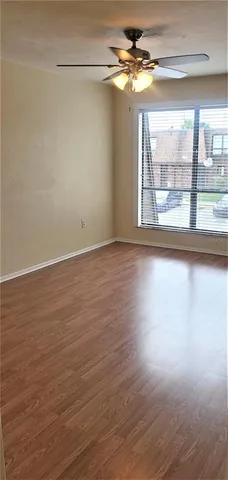 a view of empty room with wooden floor and fan