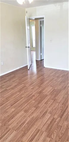 a view of empty room with wooden floor and window