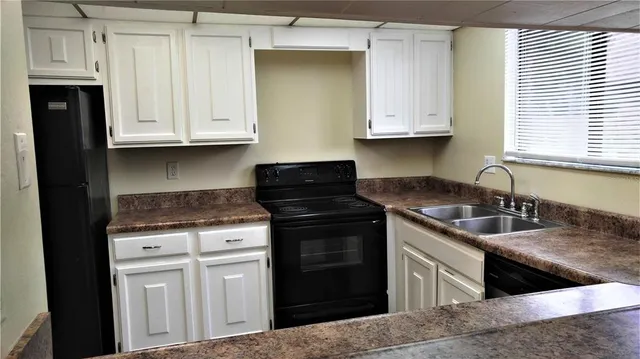 a kitchen with granite countertop a sink dishwasher stove and cabinets