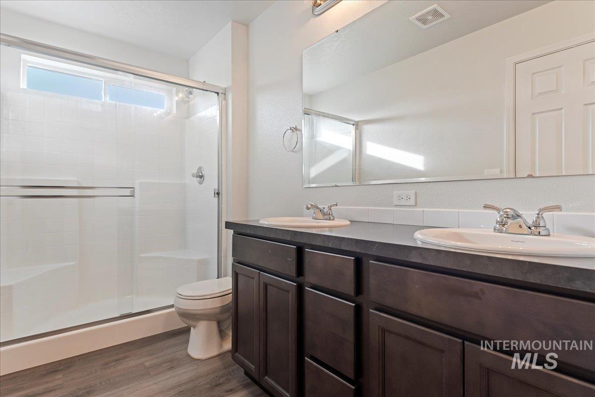 961 West Apple Pine Street Meridian, ID 83646 - Photo 11 of 30 Full bathroom featuring double vanity, a shower stall, and dark wood finished floors