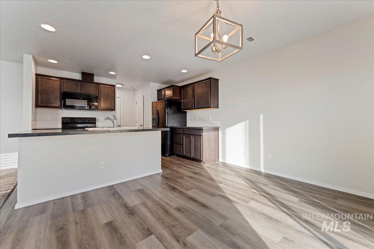 961 West Apple Pine Street Meridian, ID 83646 - Photo 30 of 30 Kitchen with dark brown cabinets, black appliances, decorative light fixtures, open floor plan, and recessed lighting