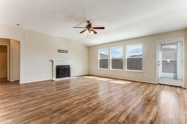 a view of an empty room with wooden floor fireplace and a window