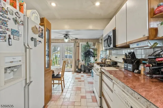 a kitchen with stainless steel appliances granite countertop a refrigerator a sink a stove and white cabinets