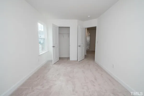 a view of an empty room with closet and a window