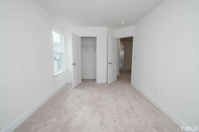 a view of an empty room with closet and a window