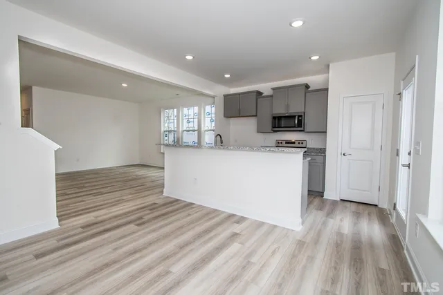 a view of kitchen with cabinets stainless steel appliances and wooden floor