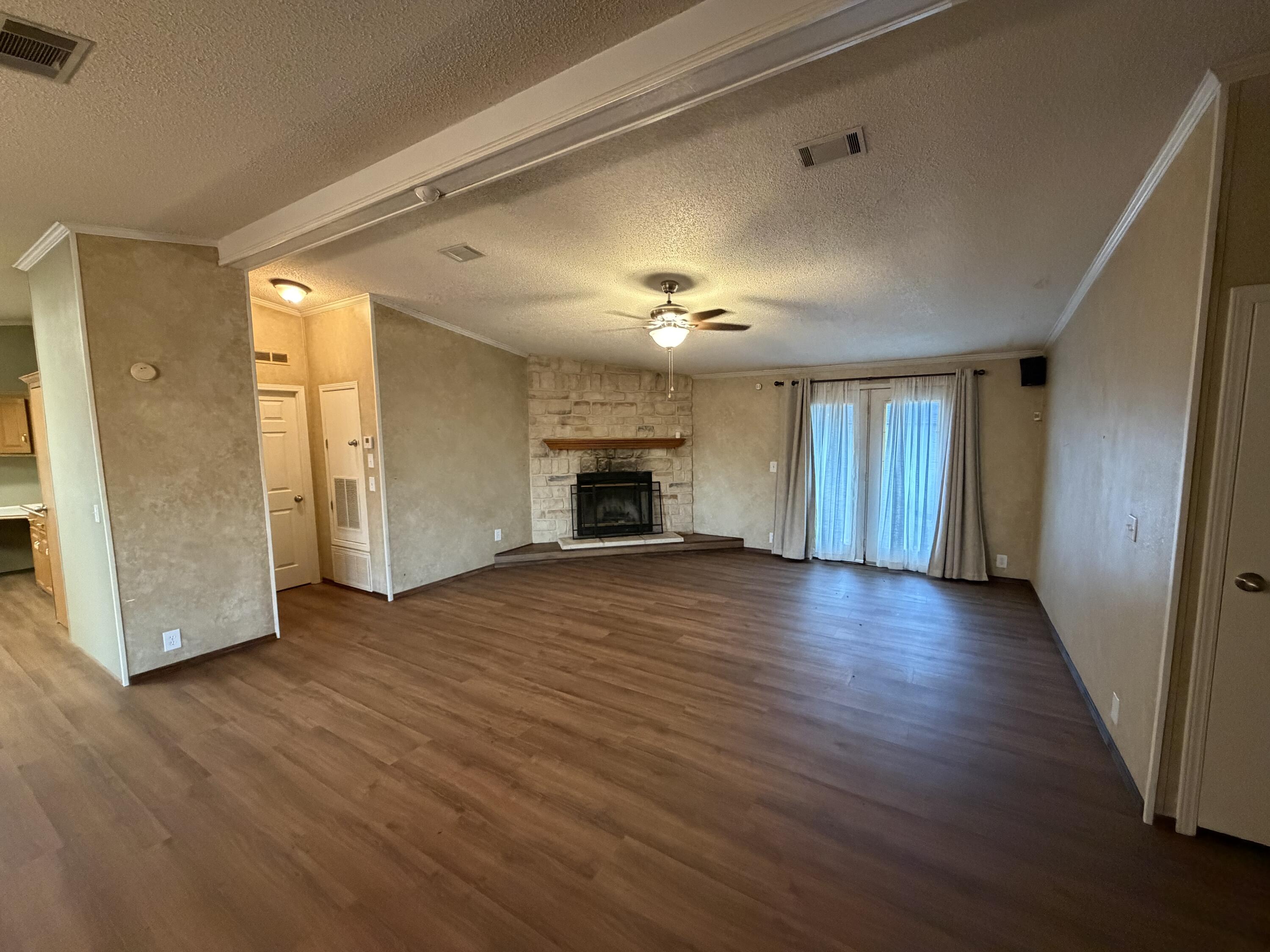 11120 Gentry Lane Slaton, TX 79364 - Photo 7 of 17 an empty room with wooden floor fireplace and windows